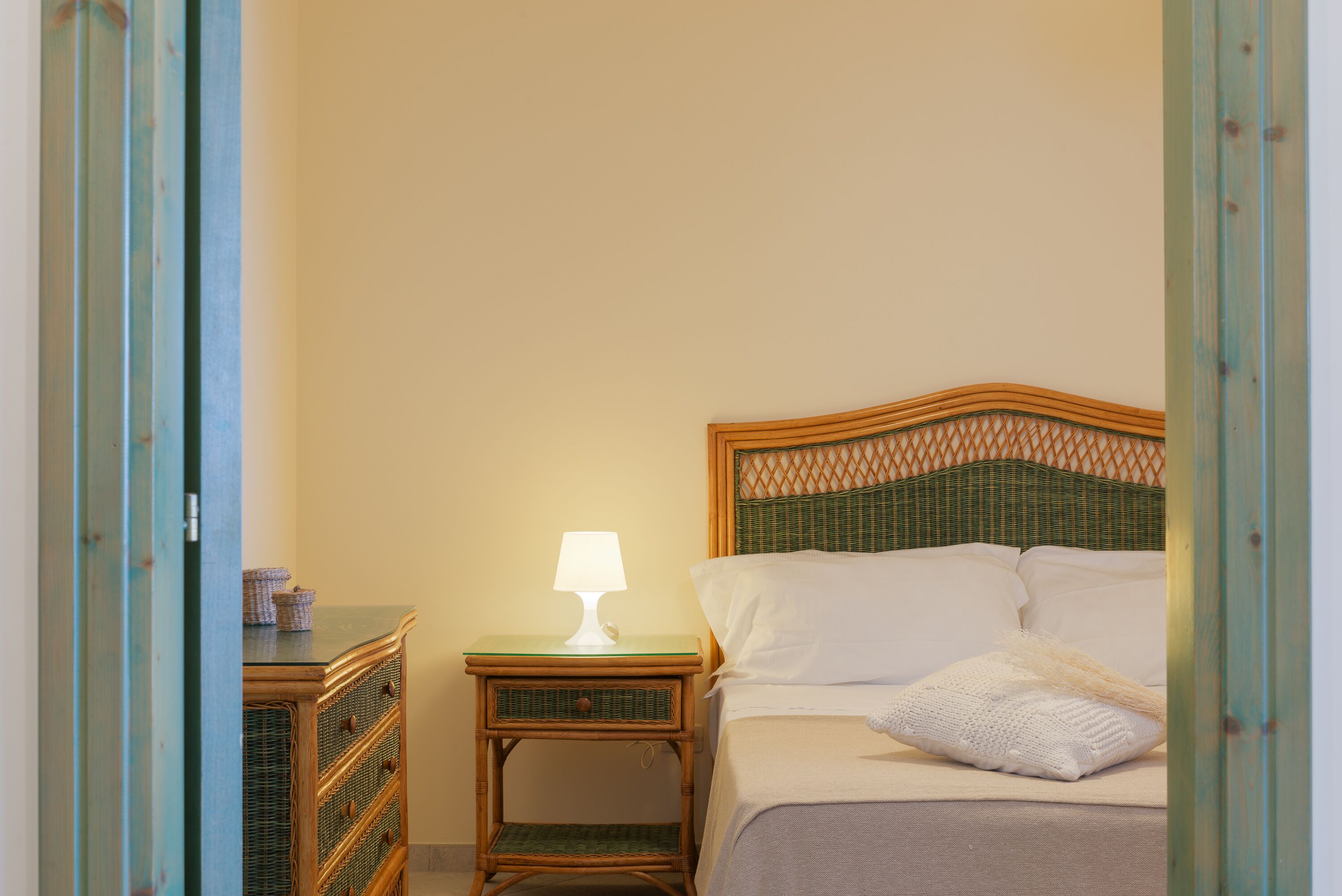 Een slaapkamer met een bed, nachtkastje met een lamp en een kledingkast.