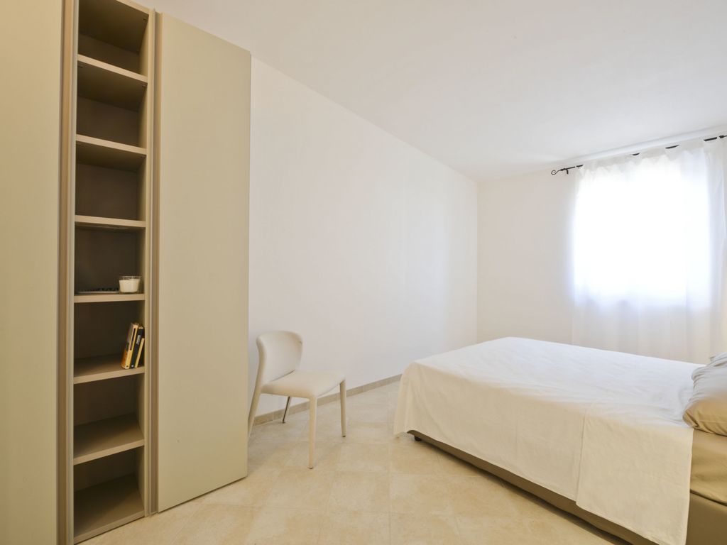 A bedroom with a bed, a chair, and a wardrobe.