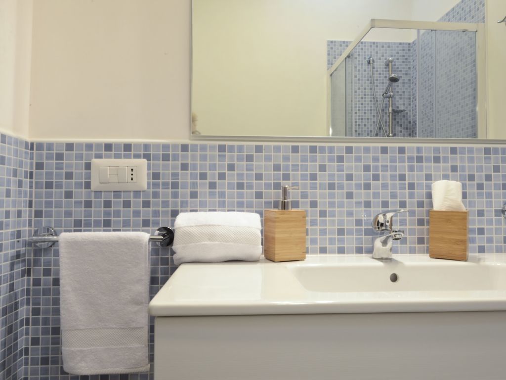 A bathroom with a white sink, blue mosaic tiles, a mirror, and a towel rack.