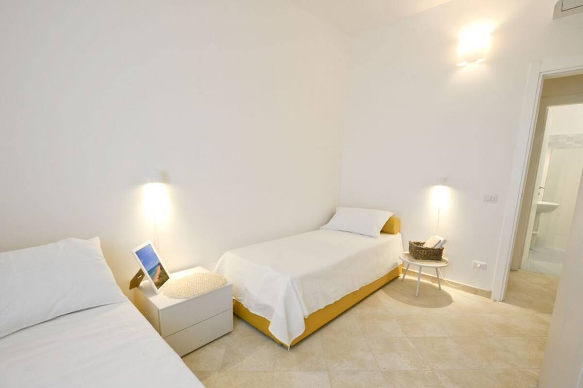 Ein Schlafzimmer mit zwei Betten, einem Nachttisch mit Lampe und einem kleinen Tisch mit Korb.