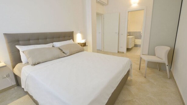 Een slaapkamer met een bed, nachtkastje en een stoel.