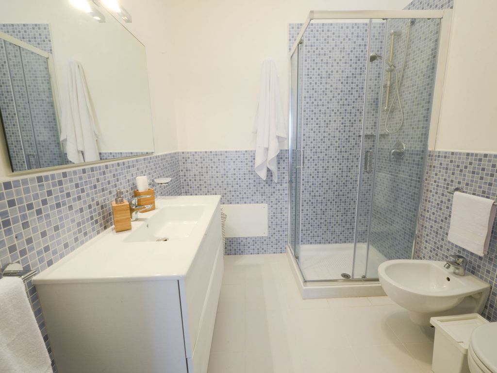 A bathroom with a white sink, a glass shower enclosure, and a white toilet.
