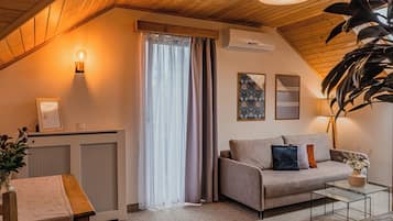 Una sala de estar acogedora con techo de madera, un sofá con cojines, una mesa de centro y una planta.