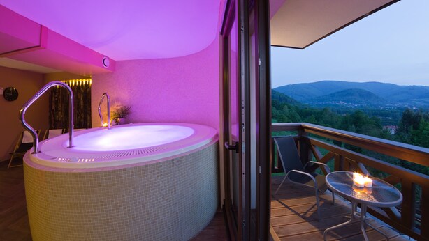 A hot tub with a panoramic view of mountains and a balcony with a table and candles. - Perła Beskidu (Ustron)