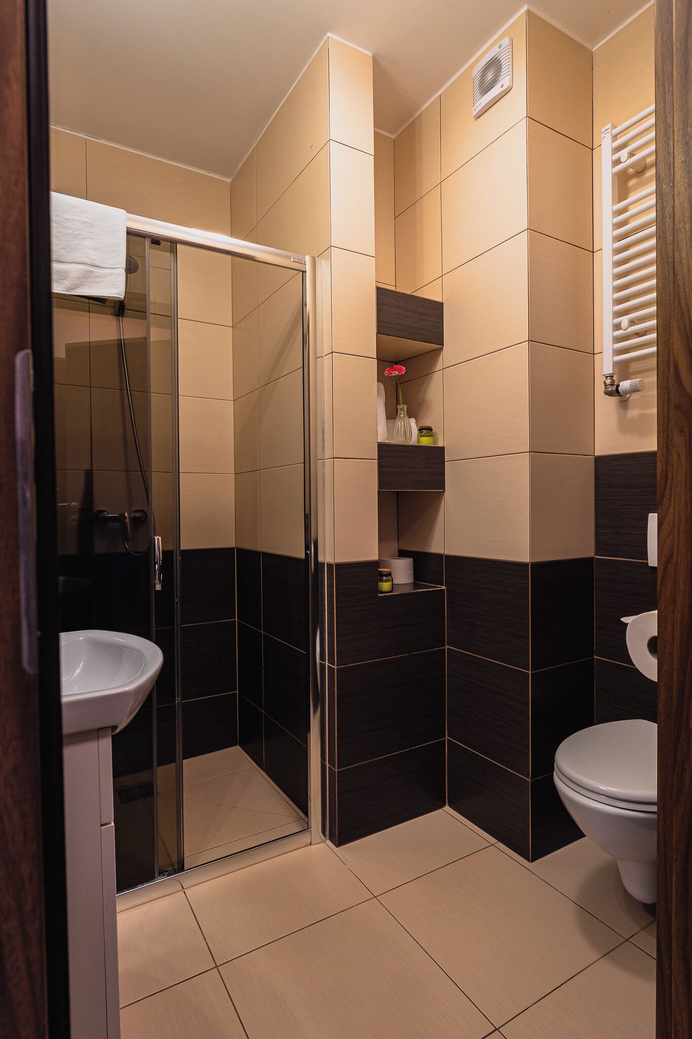 A bathroom with a glass shower enclosure, a white sink, and a toilet.