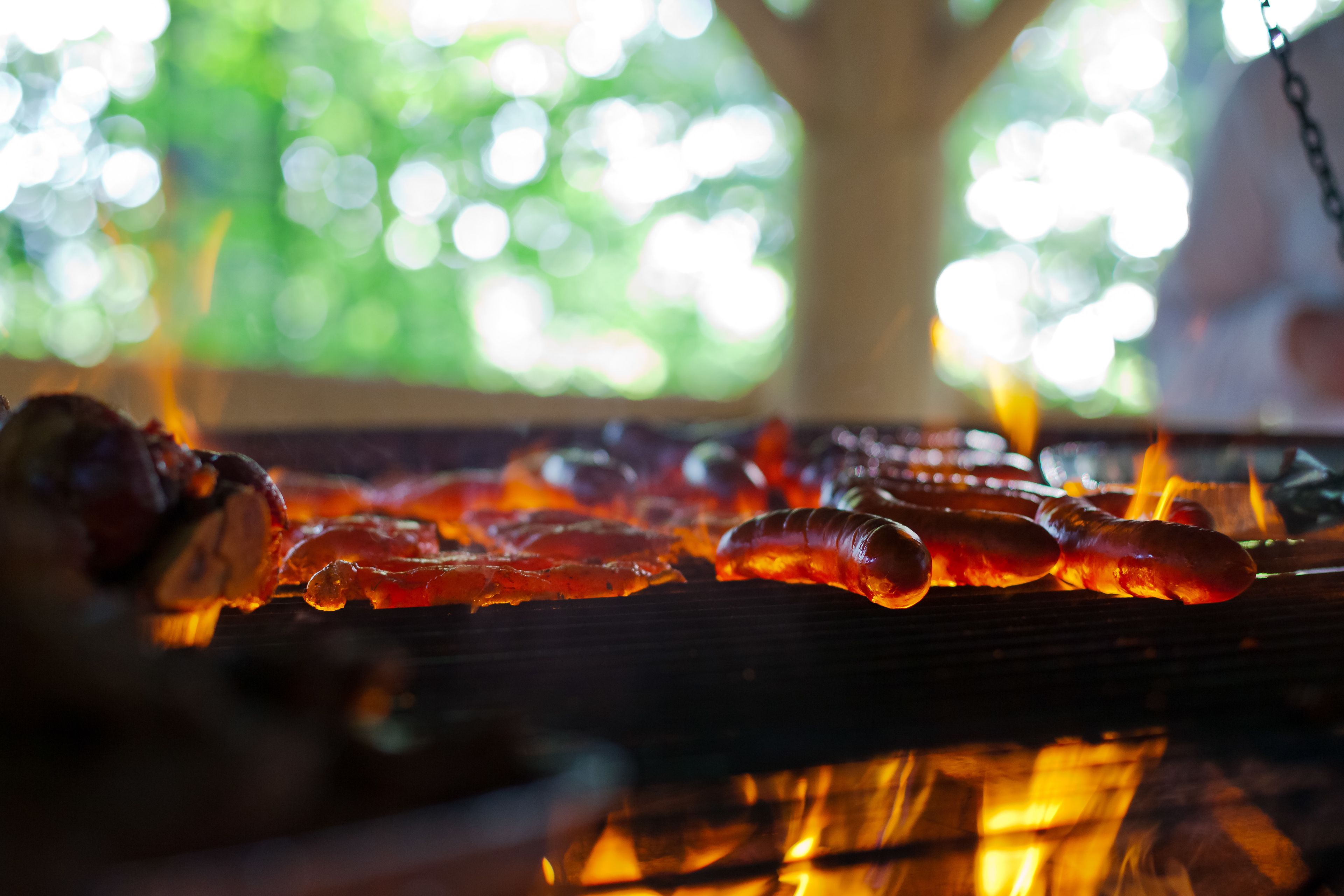 Una parrilla con salchichas cocinándose sobre fuego vivo.