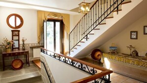En trappa med ett tr äräcke och svarta balustrar, som leder upp till en liten plattform med ett dekorativt konsolbord och en vas med blommor.