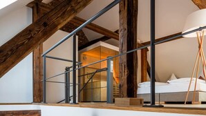 A modern loft with exposed wooden beams, a staircase, a sofa, and a bed. - Goldkind Feine Wohn & Schlafstuben (Heppenheim)