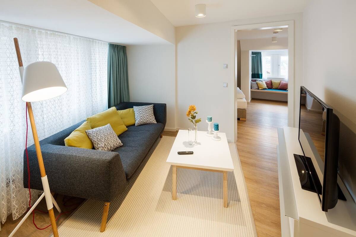 A modern living room with a grey sofa, a white coffee table, and a TV stand.