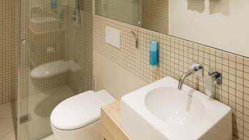 A modern bathroom with a glass-enclosed shower, a white toilet, a large sink with a mirror above, and a towel rack with two towels.