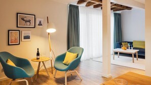 A modern living room with two teal armchairs, a wooden coffee table, and a floor lamp. - Goldkind Feine Wohn & Schlafstuben (Heppenheim)