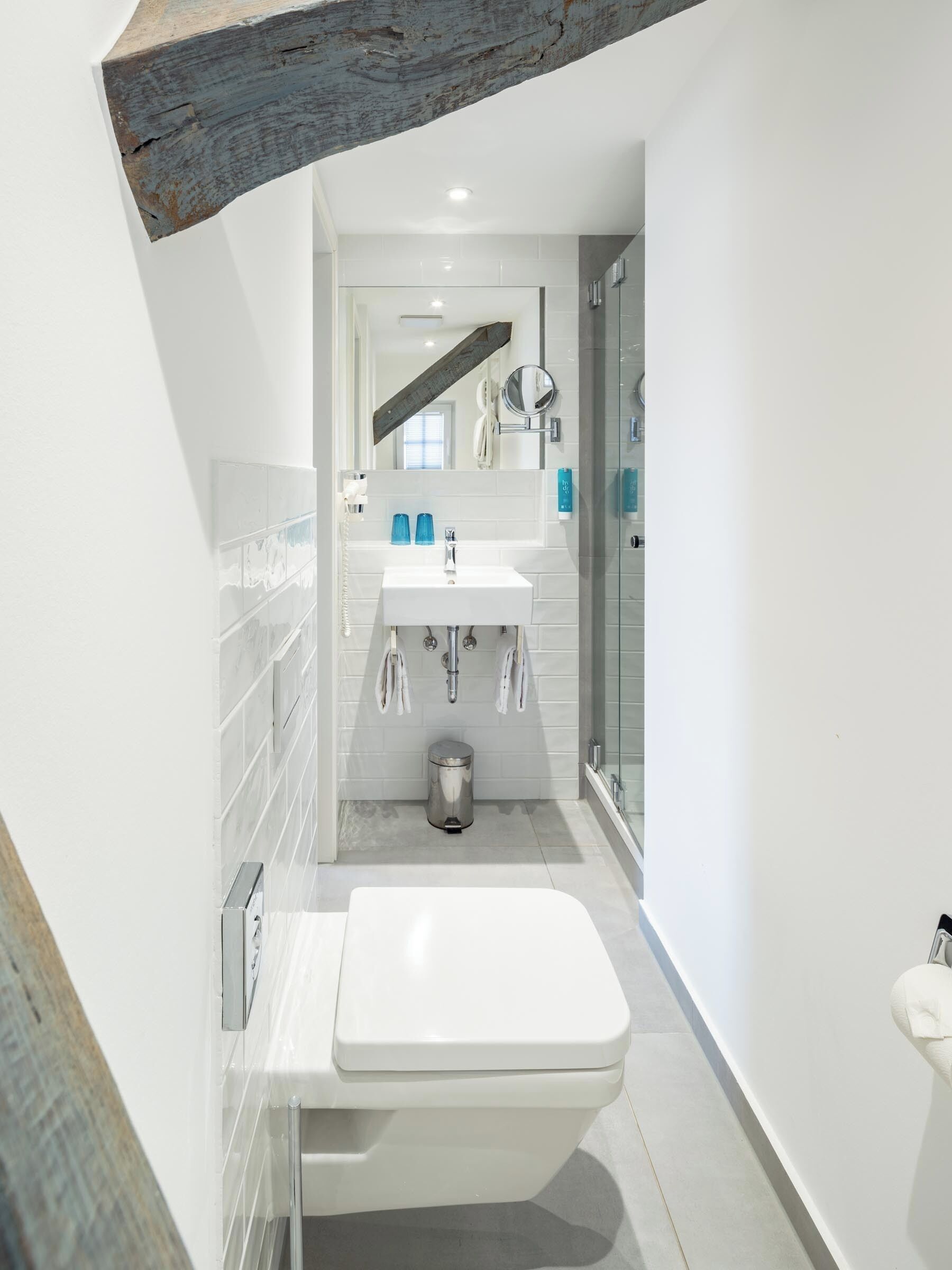 Un baño moderno con lavamanos, espejo e inodoro blancos.
