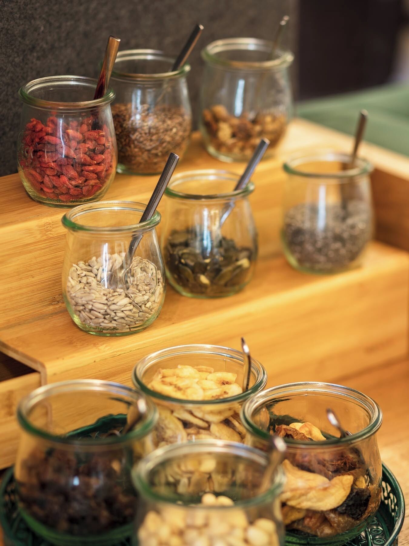 A wooden table with various glass jars containing different types of nuts and seeds.