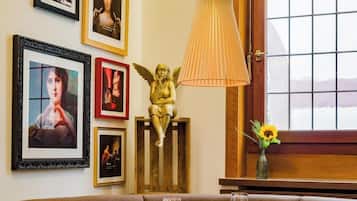 Un comedor con una mesa redonda, sillas, una pared con cuadros enmarcados, una escultura decorativa de un ángel y un ventanal con vistas.