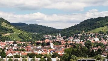 Une ville qui se distingue par une église imposante située sur une colline, entourée de collines verdoyantes et de bâtiments aux toits rouges.