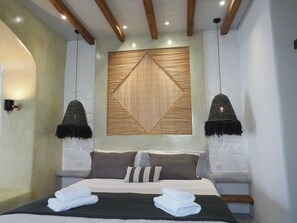 Un dormitorio moderno con una cama grande, dos lámparas fijadas a la pared y un panel de pared geométrico.