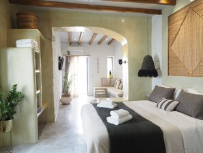 Une chambre moderne dotée d’un grand lit, d’une armoire intégrée, d’un coin salon et offrant une vue à travers une arche.
