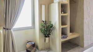 A bathroom with a large window, a towel rack, a shelf with toiletries, and a potted plant. - Aegis Royale Villa (Paros)