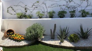 A modern building with a white exterior, a rooftop garden with various plants, and a wall-mounted irrigation system. - Aegis Royale Villa (Paros)