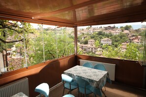 A balcony with a table and chairs, overlooking a residential area with houses and trees.