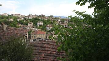 Un pueblo en una colina con edificios de tejados de teja y abundante vegetación, bajo un cielo despejado.