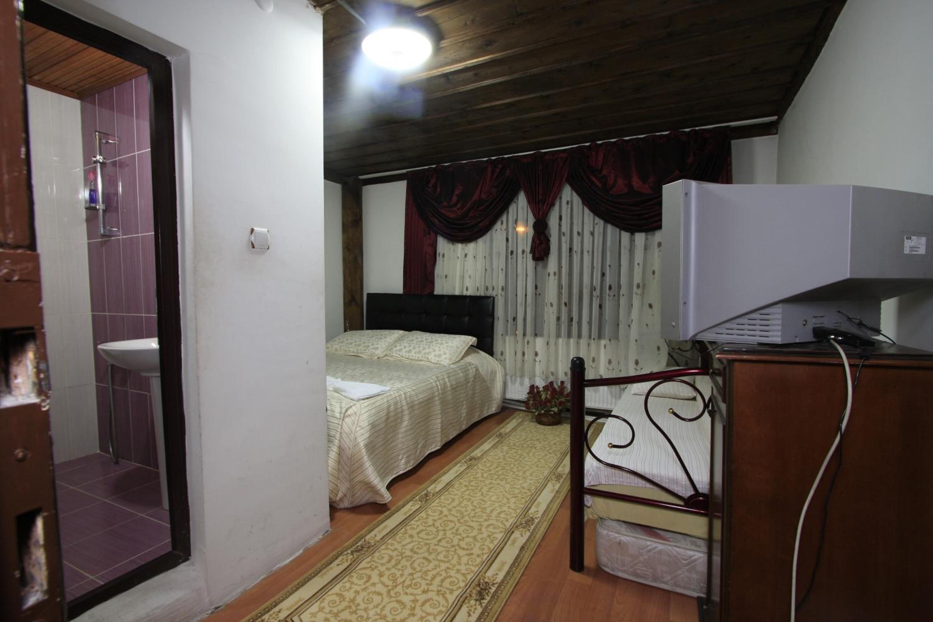 A bedroom with a bed, a bedside table, a wardrobe, a mirror, a sink, and a shower.