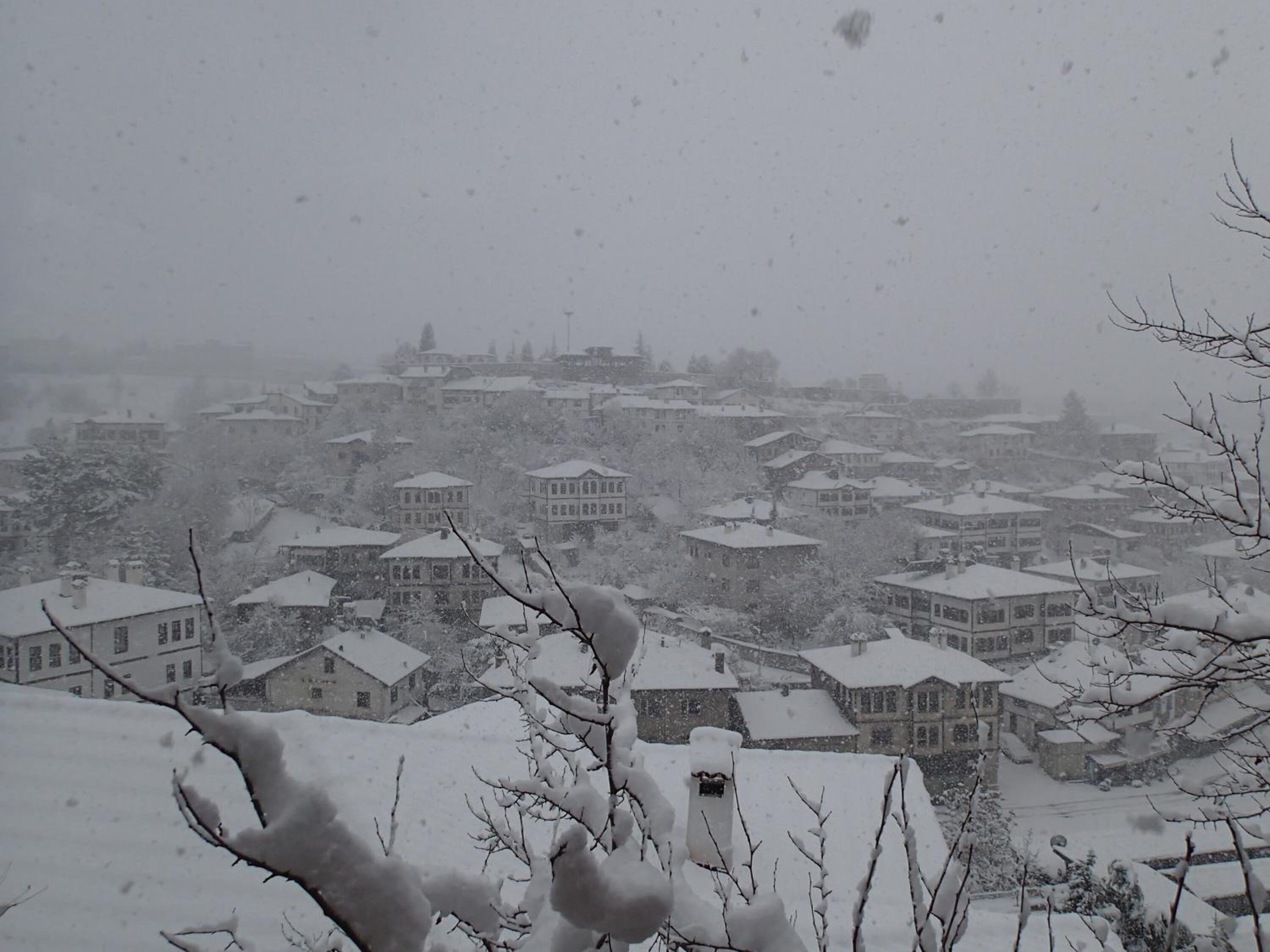 Un pueblo cubierto de nieve con edificios tradicionales y montañas al fondo.