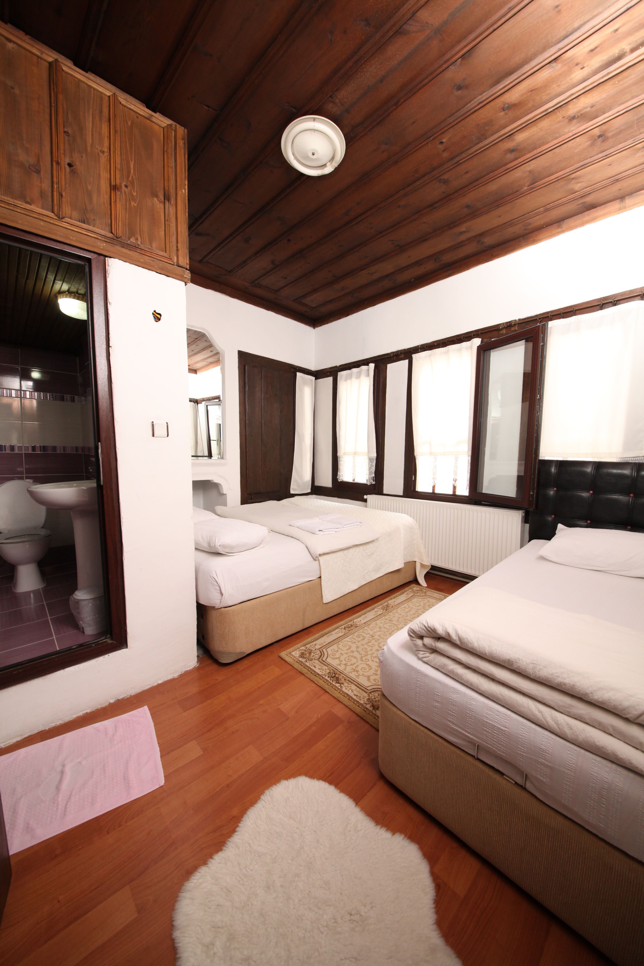 Una habitación con dos camas, techo de madera, una ventana y un radiador.