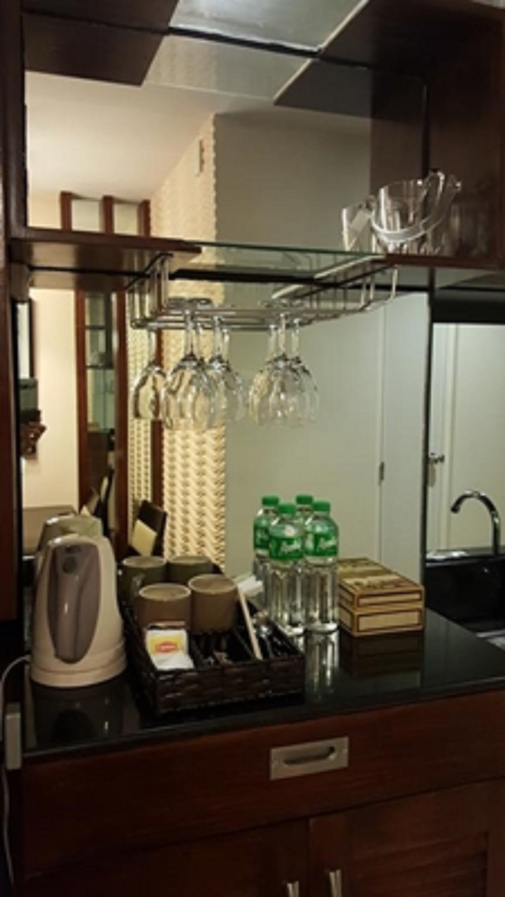 Una cocina con cafetera, hervidor y un escurridor para copas de vino.