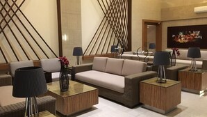 A modern lobby with a sofa, two side tables, and a decorative wall with intersecting lines. - Relaxing Wind (Tagaytay)