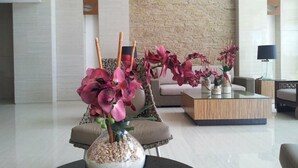 A modern lobby with a brick wall, a round table with a vase of pink flowers, and a sofa with cushions. - Relaxing Wind (Tagaytay)