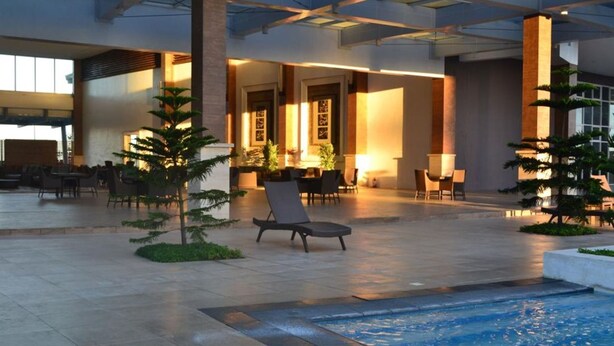 A spacious indoor area with a pool, lounge chairs, and seating areas. - Relaxing Wind (Tagaytay)