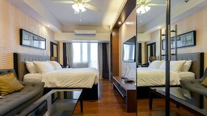 A hotel room with two beds, a sofa, a TV, and a ceiling fan. - Relaxing Wind (Tagaytay)
