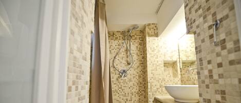 A bathroom with a toilet, shower, and sink.