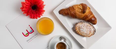 Un desayuno con un croissant, un pastel, un vaso de jugo de naranja, una flor y un menú.