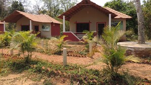 A building with a red roof and beige walls, surrounded by greenery and trees. - Jungle Nest Homestay (Joida)