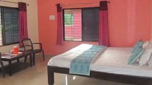 A bedroom with a bed, a desk, and a chair. - Jungle Nest Homestay (Joida)