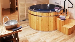Un hidromasaje de madera con lavamanos integrado y un pequeño rincón de estar.