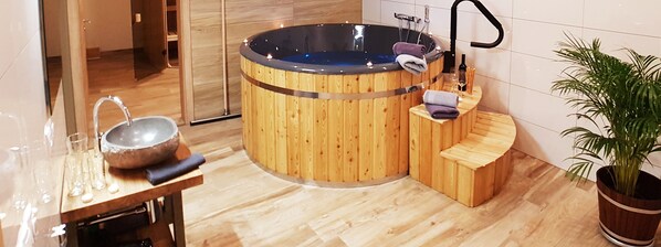 Een houten jacuzzi met een ingebouwde wasbak en een klein zitgedeelte.