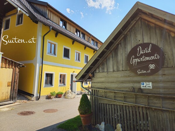 En gul bygning med et skilt for David Apartments og et skilt for Suiten.at.