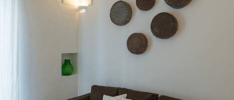 Ein Wohnzimmer mit einem braunen Sofa, weißen Kissen und einer Wandleuchte.