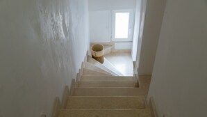 Una escalera que lleva a una habitación con una ventana y un bote de basura.