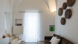 Una sala de estar moderna con una escalera, un sofá marrón, un florero verde y adornos en la pared.