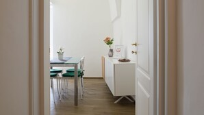 Un pasillo que conduce a un comedor con una mesa, sillas y un armario.