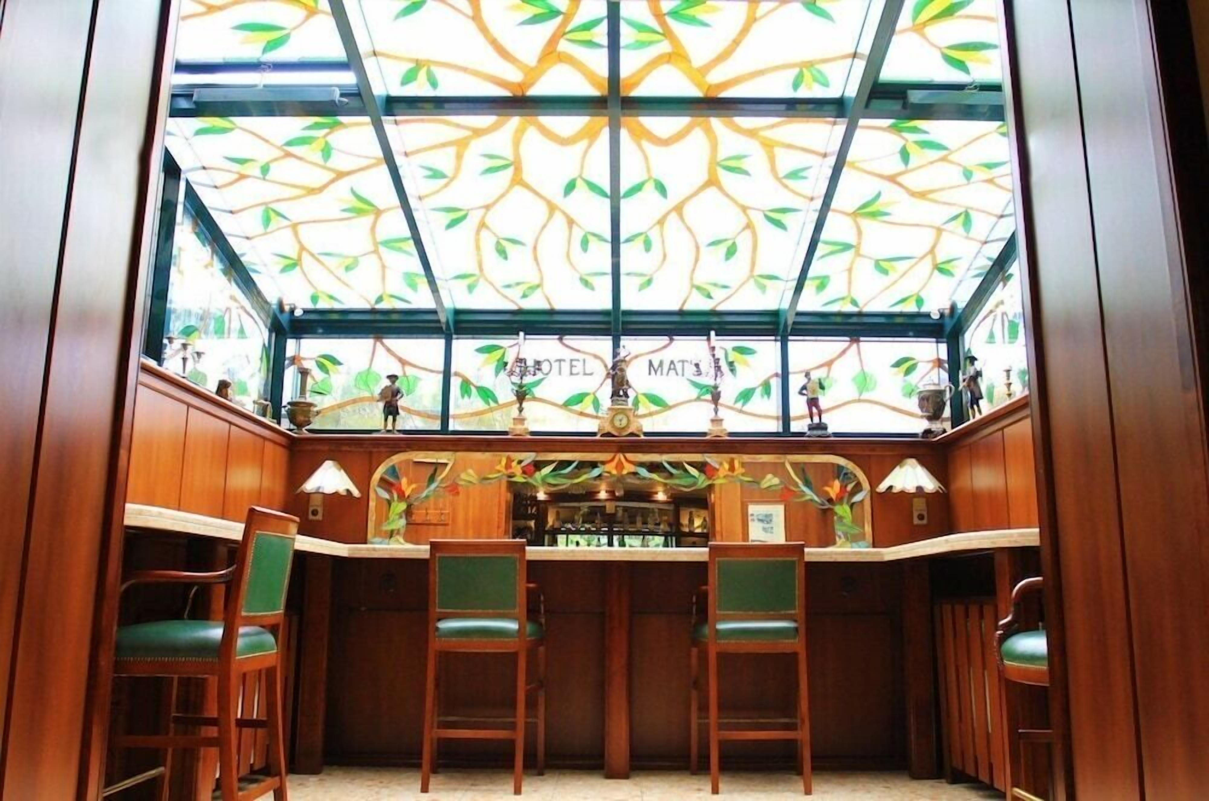 A bar area with wooden chairs and a ceiling with a leaf pattern.