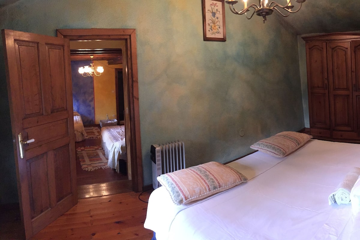 A bedroom with a large bed, wooden wardrobe, and a radiator.