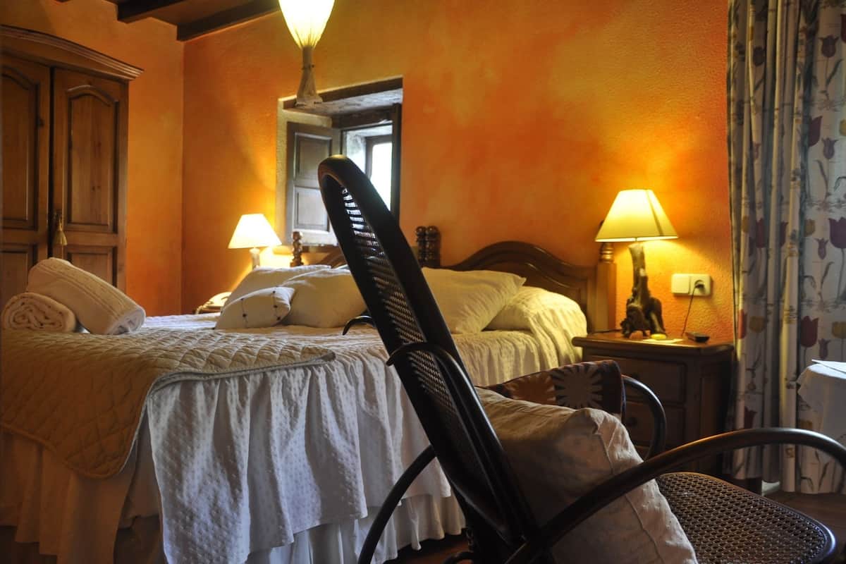 A hotel room with a bed, two bedside lamps, a chair, and a nightstand with a lamp.