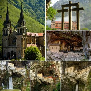 A church with a bell tower, a cross, and a building built into a cliffside. - Hotel Peñalba (Cangas de Onis)
