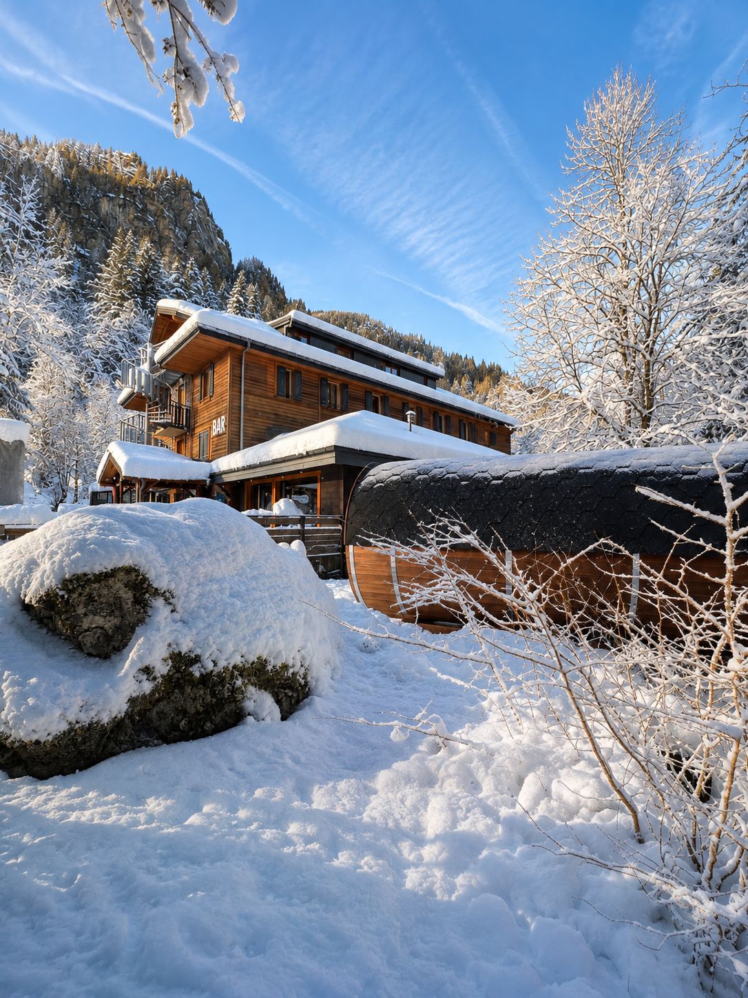 A wooden lodge with a bar, surrounded by snow-covered trees and a mountain backdrop.