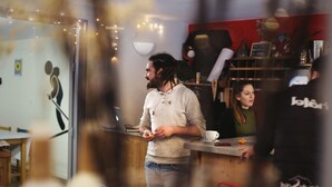 A person standing at a counter in a cafe with a laptop and a cup on the table. - 1861 Châtel Hostel (Chatel)